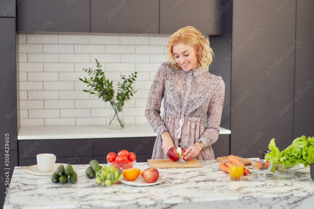 Young woman cuts an apple in a vegetarian kitchen. Young woman cuts an apple in a vegetarian kitchen.
