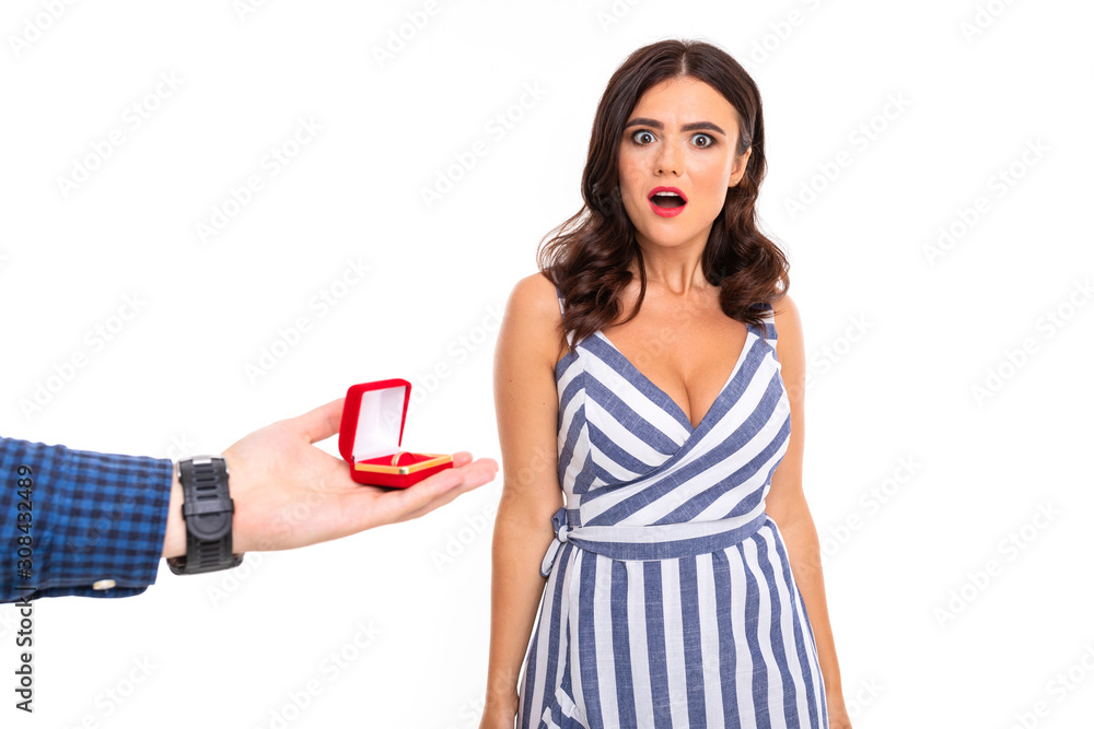 man makes a proposal to a girl and gives a ring and a surprised girl in a dress on a white background man makes a proposal to a girl and gives a ring and a surprised girl in a dress on a white background