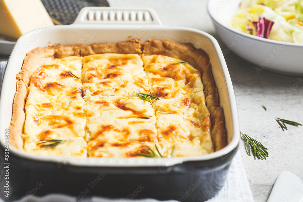 Cheese pie with rosemary in black oven dish, gray background. Cheese pie with rosemary in black oven dish, gray background.