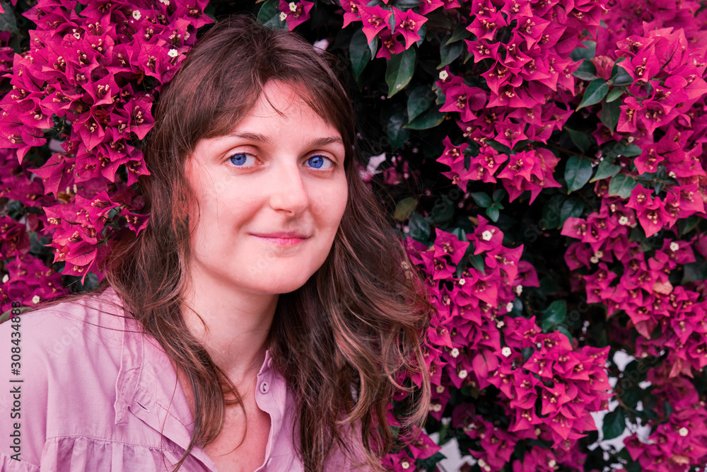 Girl smiling next to the tree blooming with large bright flowers, copy space. Young woman on a background of red flowers. portrait close-up Girl smiling next to the tree blooming with large bright flowers, copy space. Young woman on a background of red flowers. portrait close-up