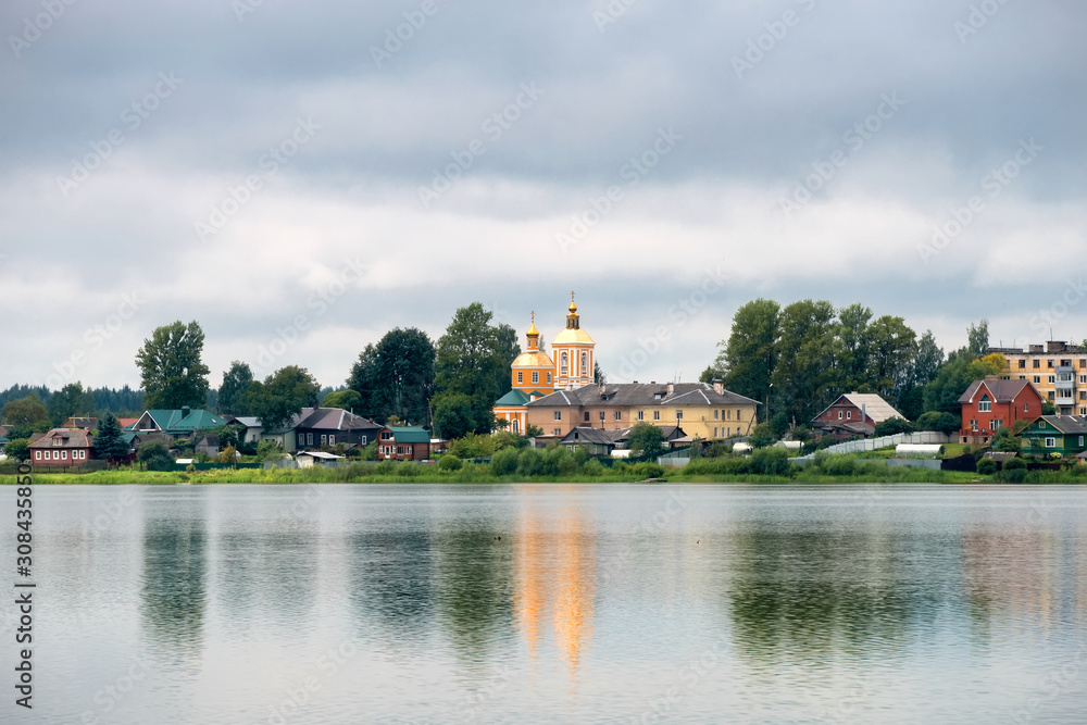 View of the Trinity Church and residential buildings on Kirov street across Lake Bologoe. City Bologoe, Tver region, Russia