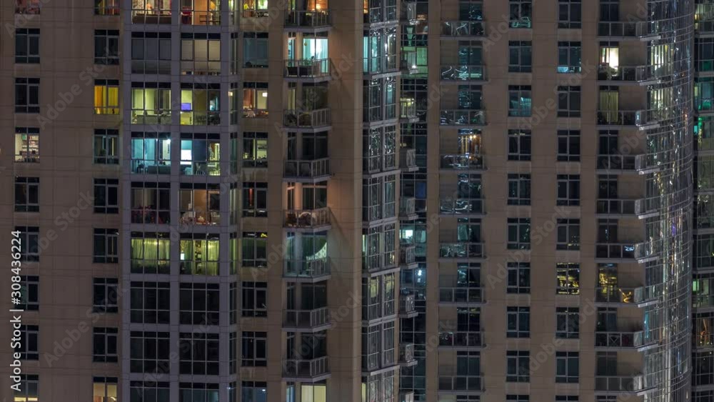 Windows of the multi-storey building with lighting inside and moving people in apartments timelapse. Aerial view of modern residential skyscrapers in Dubai downtown. Windows of the multi-storey building with lighting inside and moving people in apartments timelapse. Aerial view of modern residential skyscrapers in Dubai downtown.