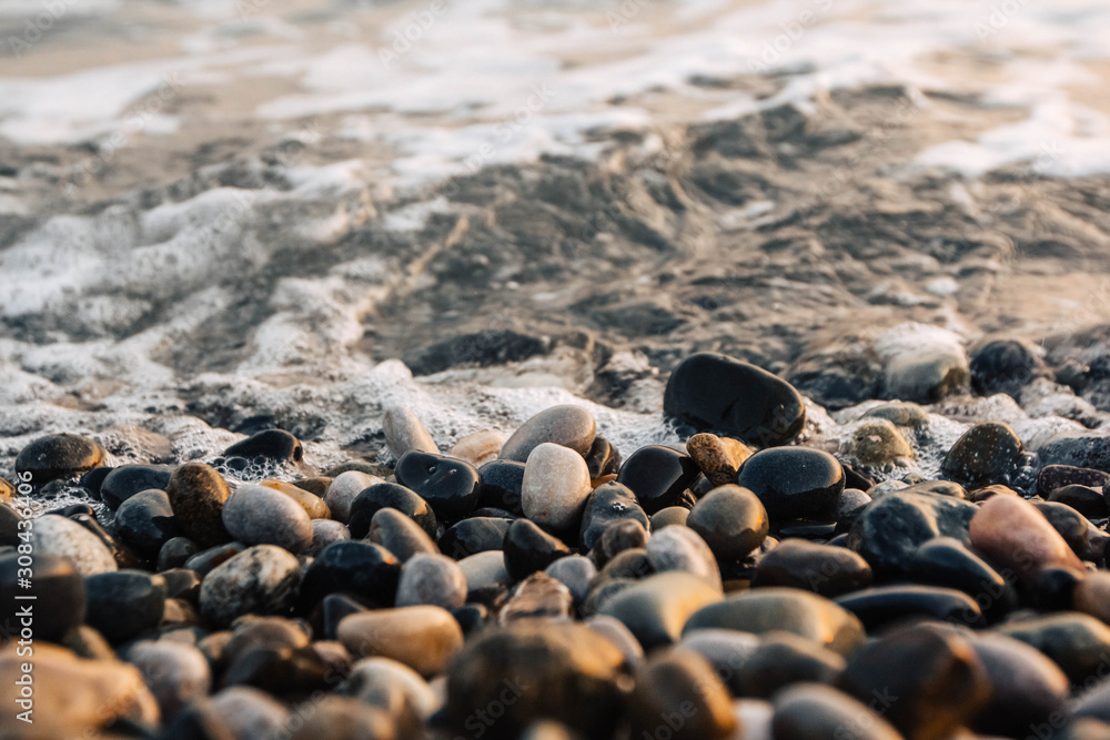 Small stones by the sea with bokeh effect. Blurred decorative background, place for text. Summer wallpaper, sunny sunset light Small stones by the sea with bokeh effect. Blurred decorative background, place for text. Summer wallpaper, sunny sunset light