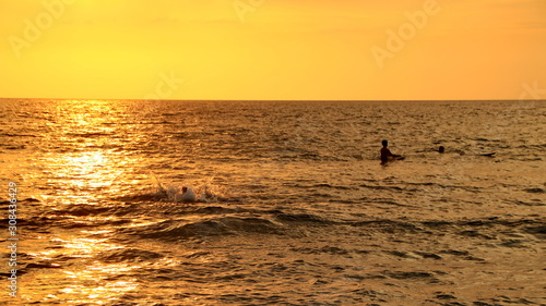 Documentation of surfers in action at dusk with a golden color and dark, unfocused and dark on the beach of Senggigi Lombok, West Nusa Tenggara Indonesia, 27 November 2019 © onyengradar