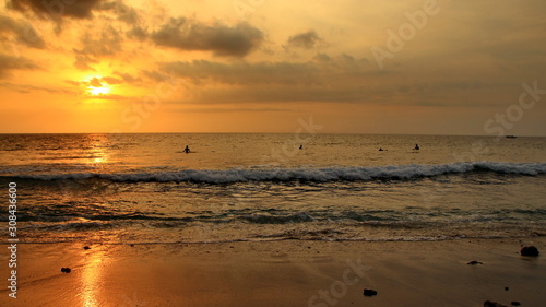 Documentation of surfers in action at dusk with a golden color and dark  unfocused and dark on the beach of Senggigi Lombok  West Nusa Tenggara Indonesia  27 November 2019