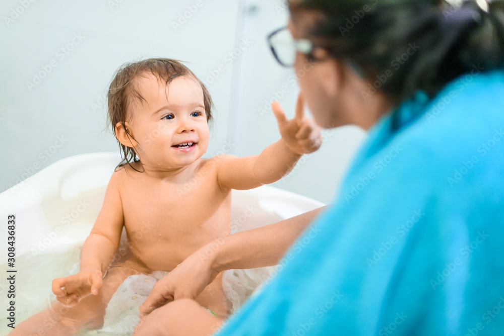 Happy 1 year old Baby in bathtub taking bath in bathroom with mother. Happy 1 year old Baby in bathtub taking bath in bathroom with mother.
