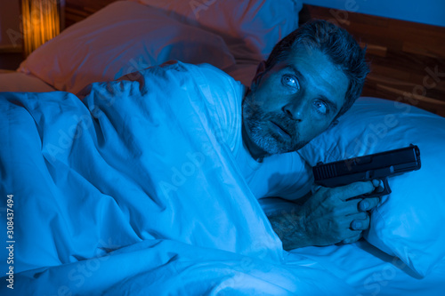 Fotografie night edgy portrait of young stressed and paranoid American man lying on bed una