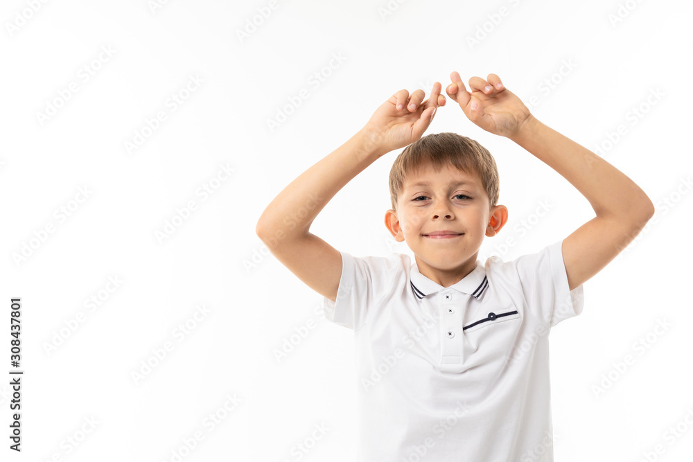 cute boy with bangs in a white T-shirt and glasses with crossed fingers on a white background with copy space cute boy with bangs in a white T-shirt and glasses with crossed fingers on a white background with copy space