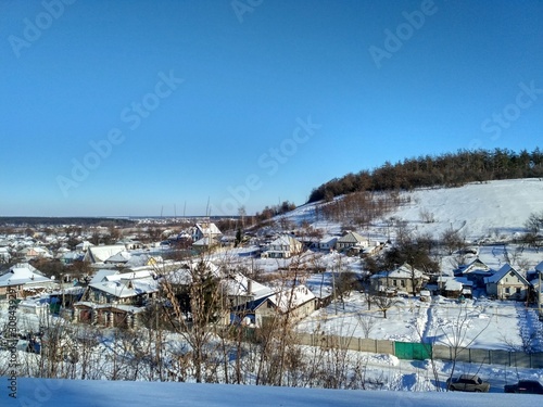 winter landscape with village and hillock