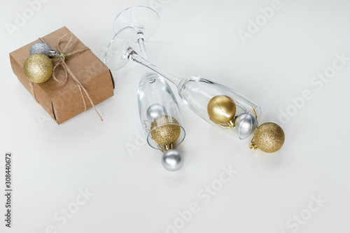 Paper gift box wrapped with rope and champagne glasses filled with Christmas decorations, isolated on white background. Presents and holidays concept.