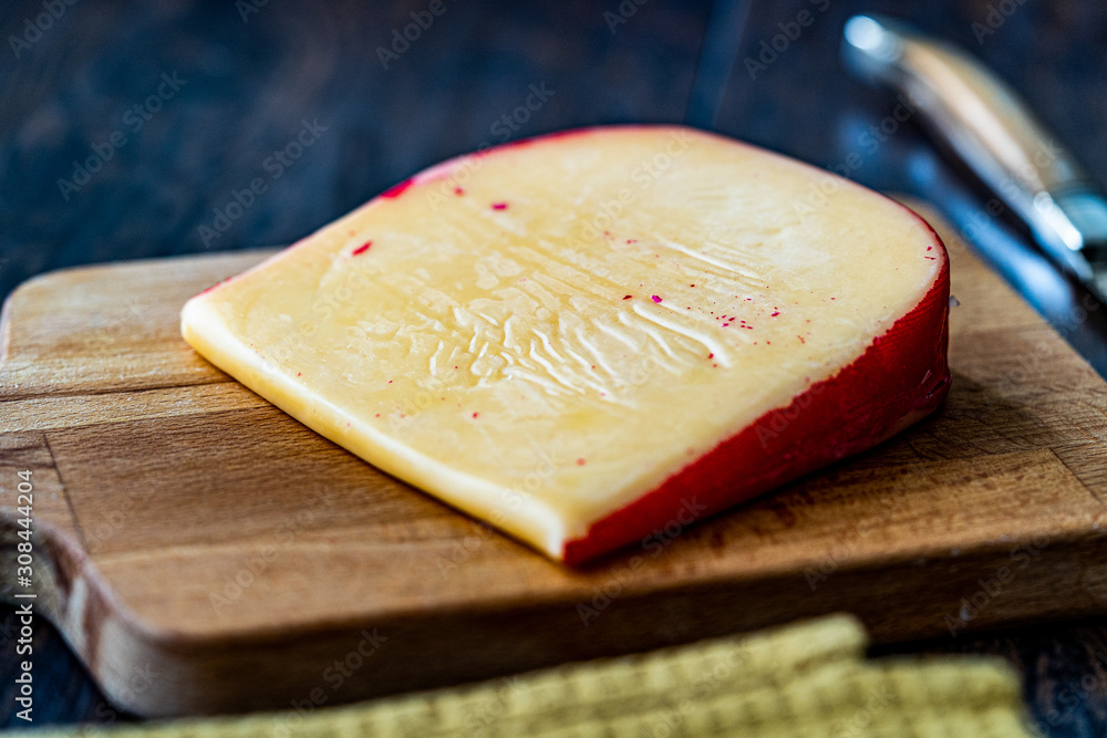 Hard Dutch Gouda Cheese, Close-up on Wooden Board with Knife. Hard Dutch Gouda Cheese, Close-up on Wooden Board with Knife.
