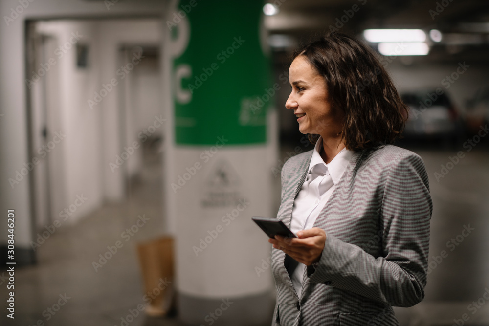 Young businesswoman using phone in garage	