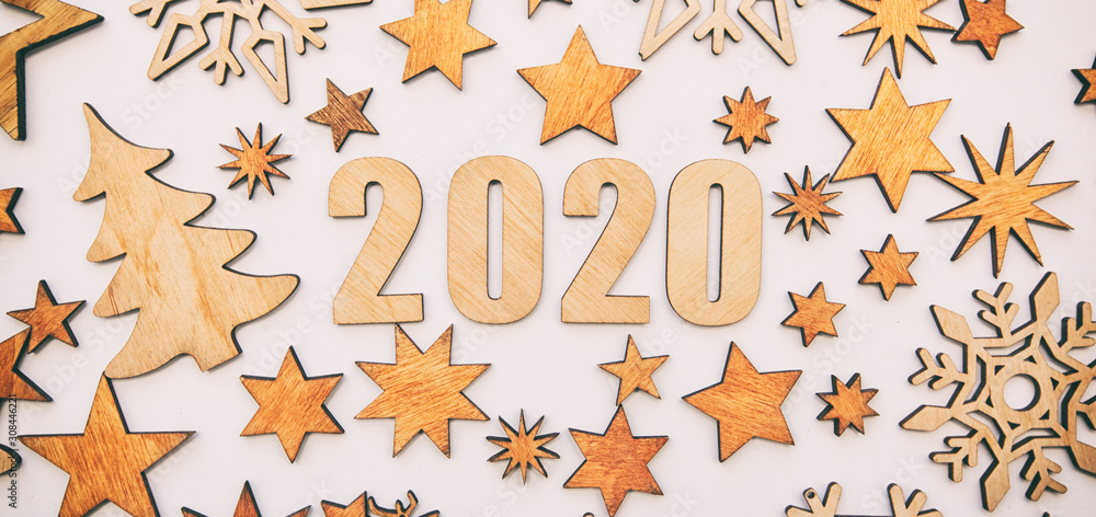 The beautiful christmas background with a lot of small wooden decorations and wooden numbers 2020 on the white desk. The beautiful christmas background with a lot of small wooden decorations and wooden numbers 2020 on the white desk.