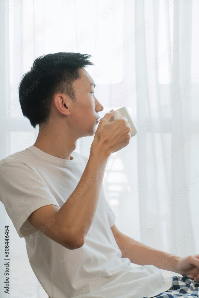 happy attractive man drinking in the morning in bedroom happy attractive man drinking in the morning in bedroom