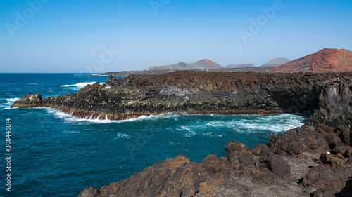 Tourists visiting popular tourist attraction "Los Hervideros", the stretch of bizarre-shaped cliffs and underwater caves formed by lava solidification and erosion