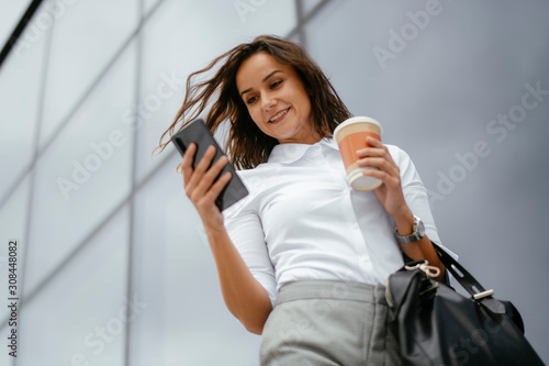 Businesswoman using phone. Beautiful young woman outdoors. 