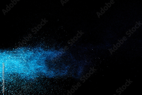 Abstract brown powder explosion. Closeup of blue dust particle splash isolated on black background.