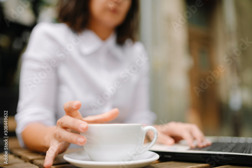 Close up of businesswoman holding cup of coffee and working outdoors. 
