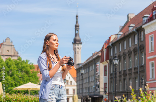 Attractive young girl traveling and exploring beautiful old town. Tourist with a retro camera on a vacation.