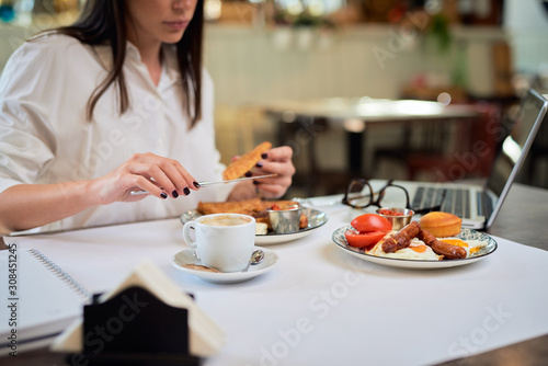 Close up of attractive hungry brunette having french toast for breakfast while sitting in restaurant.