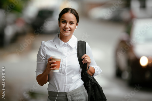 Young businesswoman drinking coffee. Beautiful student walking around the city.. 