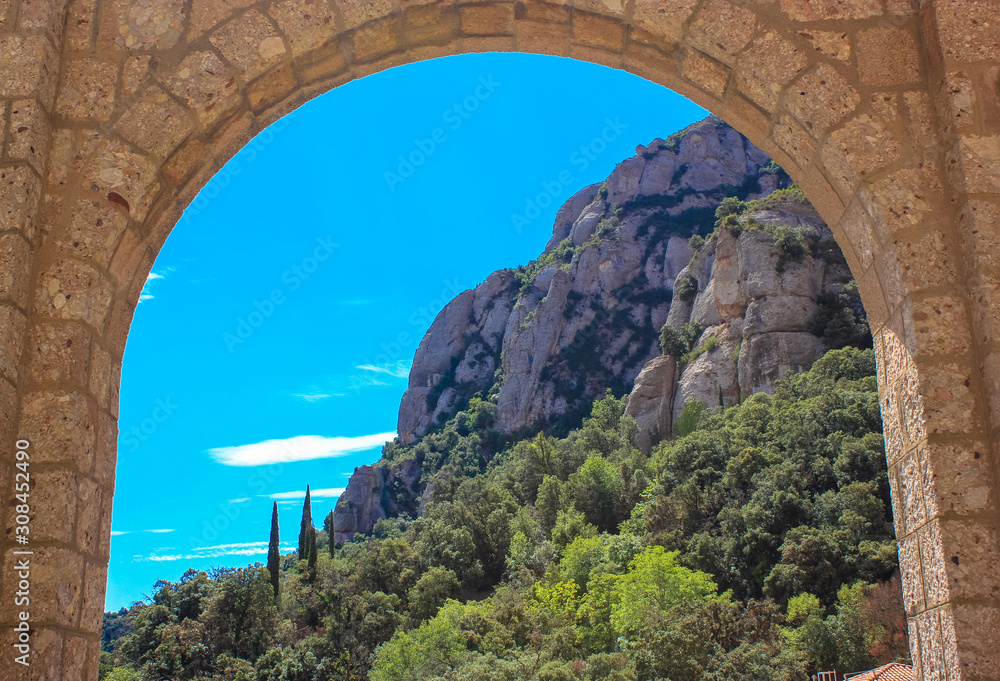 An ancient arch and a view of the blue sky, cypresses, mountains.