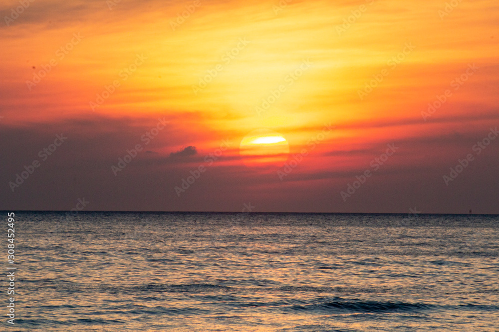 orange sun in a sky on fire at sunrise on the ocean