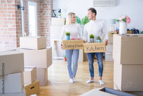 Young beautiful couple moving cardboard boxes at new home