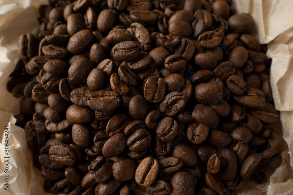 Brown coffee beans in a parchment paper saucer. The view from the top. The concept of love for coffee. Brown coffee beans in a parchment paper saucer. The view from the top. The concept of love for coffee.