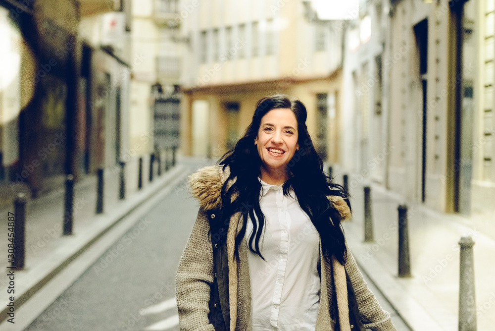 Fototapeta premium Middle-aged woman smiling and laughing happily walking through the city.