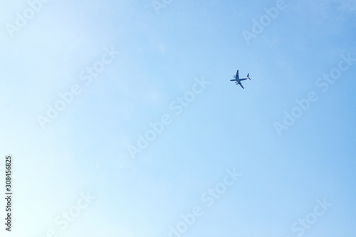 Plane flies high in blue sky from right to left