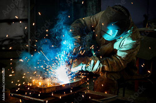 Welder works with a metal product. Beautiful sparks in the dark photo