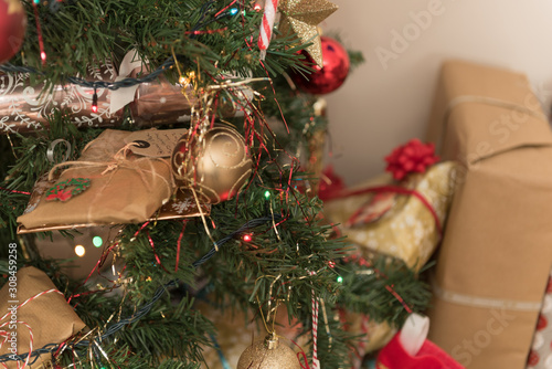 presents on Christmas tree close up with decorations and lights photo