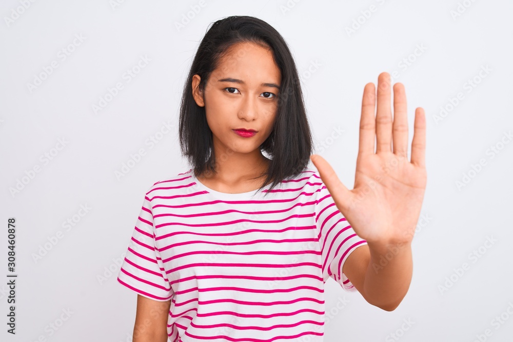 Young chinese woman wearing striped t-shirt standing over isolated white background doing stop sing with palm of the hand. Warning expression with negative and serious gesture on the face. Young chinese woman wearing striped t-shirt standing over isolated white background doing stop sing with palm of the hand. Warning expression with negative and serious gesture on the face.