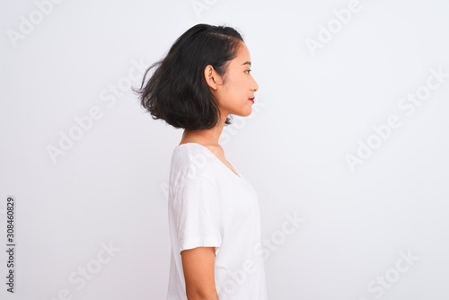 Young chinese woman wearing casual t-shirt standing over isolated white background looking to side, relax profile pose with natural face with confident smile.