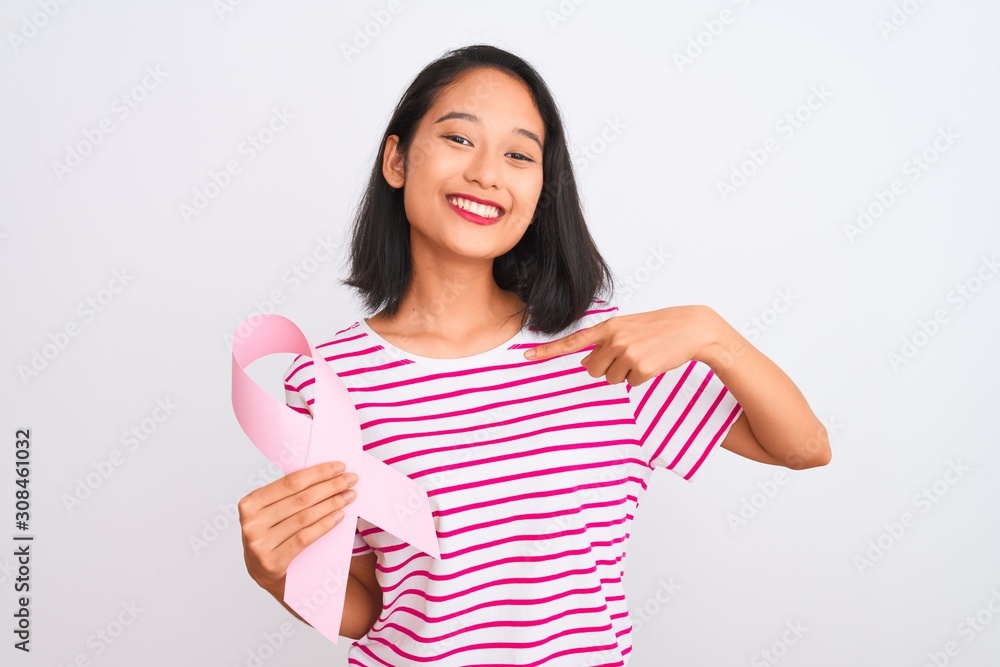 Young beautiful chinese woman holding cancer ribbon over isolated white background with surprise face pointing finger to himself Young beautiful chinese woman holding cancer ribbon over isolated white background with surprise face pointing finger to himself