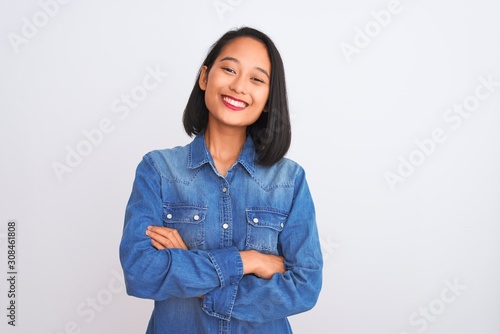 Fotografie Young beautiful chinese woman wearing denim shirt standing over isolated white background happy face smiling with crossed arms looking at the camera