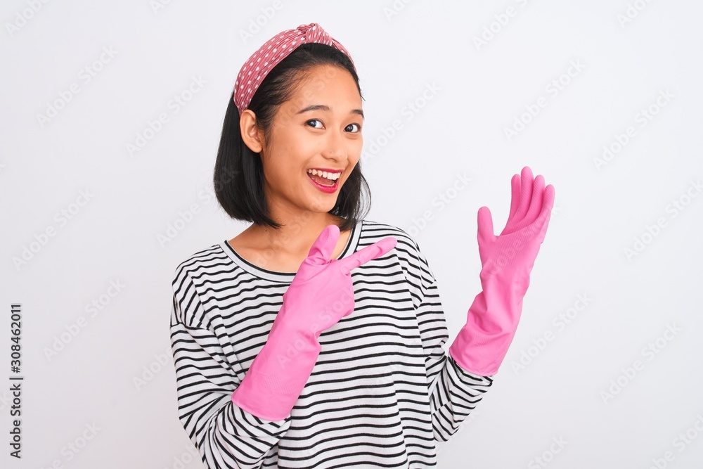 Young chinese cleaner woman cleaning using gloves over isolated white background very happy pointing with hand and finger Young chinese cleaner woman cleaning using gloves over isolated white background very happy pointing with hand and finger