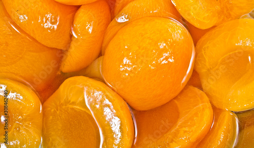 Fotografi Canned peach halves in syrup. Background.