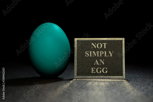 tean egg on a black background with a sign on which is written not simply an egg photo