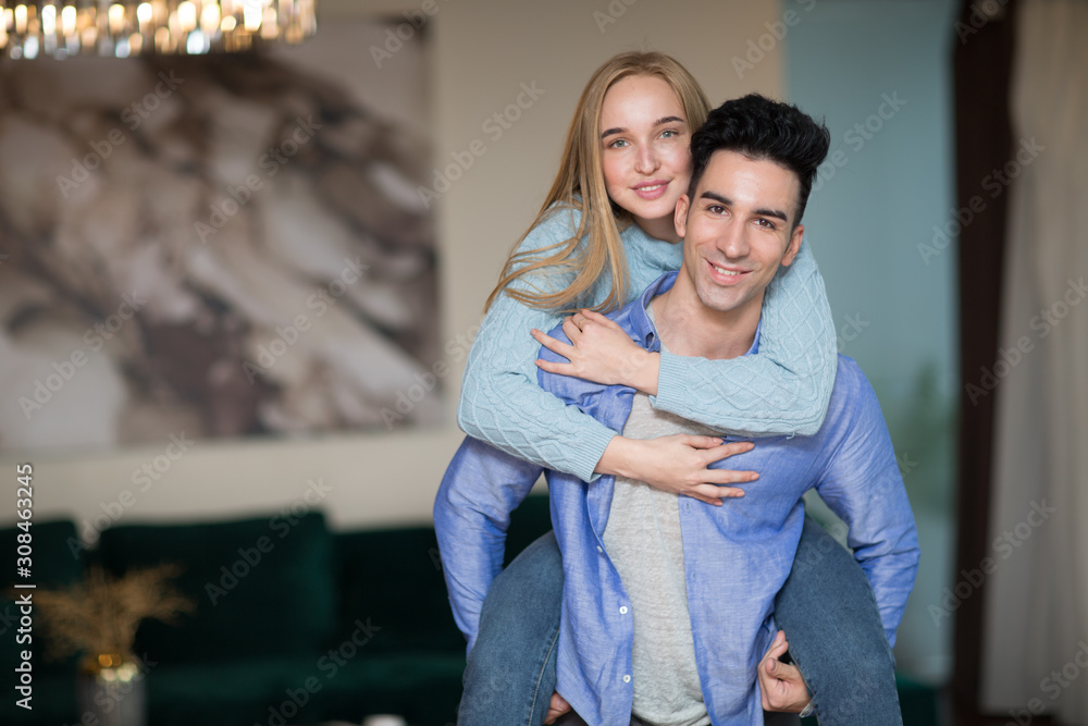 Fototapeta premium Happy young couple. Positive man and woman peggyback portrait. Hug and happy.