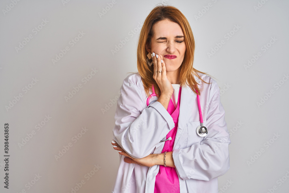 Redhead caucasian doctor woman wearing pink stethoscope over isolated background touching mouth with hand with painful expression because of toothache or dental illness on teeth. Dentist concept.