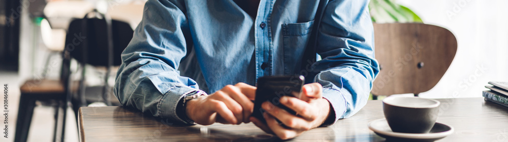 Handsome bearded hipster man use smartphone with coffee at table in cafe.Communication and technology concept Handsome bearded hipster man use smartphone with coffee at table in cafe.Communication and technology concept