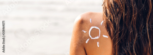 Woman wearing two piece bikini applying suncream with sun drawn on back on the tropical beach.Summer vacations photo