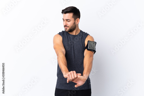 Young sport handsome man with beard over isolated white background stretching arm © luismolinero