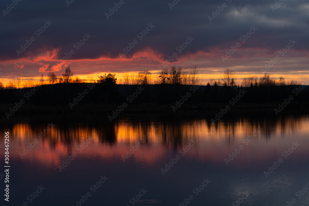Wonderful sunset over the water, colorful clouds and the reflection of light in the lake