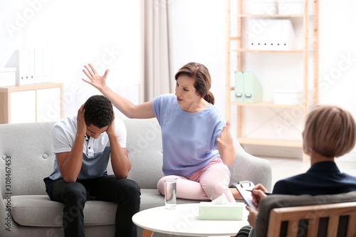 Psychotherapist working with African-American teenage boy and his mother in office