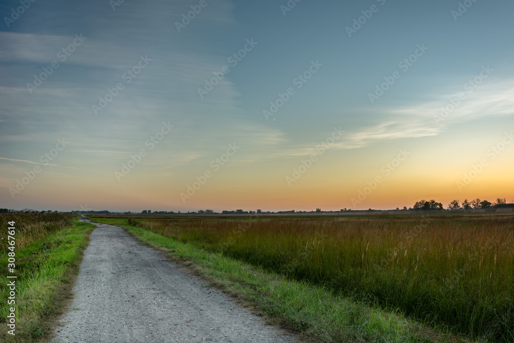 Gravel road through the meadow, horizon and sky after sunset Gravel road through the meadow, horizon and sky after sunset