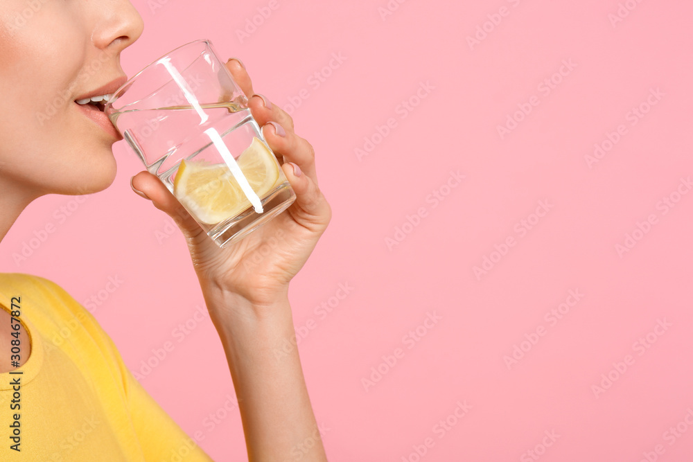Young woman drinking tasty lemon water on pink background, closeup. Space for text Young woman drinking tasty lemon water on pink background, closeup. Space for text