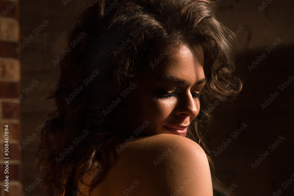 Close up. Loft, low key. Portrait of sensual pin-up girl with a naked rounded shoulder.